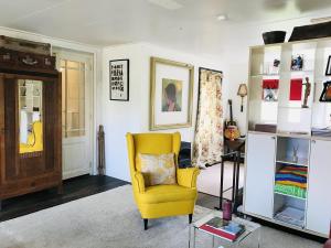 ein Wohnzimmer mit einem gelben Stuhl und einem Schreibtisch in der Unterkunft De Fryske Wyn in Ferwerd