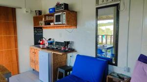 a kitchen with a blue chair and a microwave at Caminho das Dunas - Studios próx Praia do Rosa e Ouvidor in Praia do Rosa
