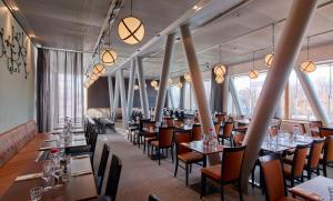 um restaurante com mesas e cadeiras e janelas grandes em Scandic Talk em Estocolmo