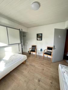 a bedroom with a bed and two chairs at Danhostel Sandvig in Sandvig