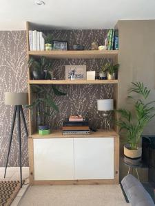 a room with a book shelf with plants and two lamps at Fairhaven 