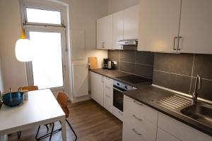 uma cozinha com armários brancos, uma mesa e um lavatório em Sanierter Altbau, 2 Zimmer, 24-7 Check-in em Kiel