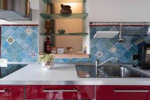 una cucina con armadi rossi e lavandino di La Finestra sulle Eolie a Reitano