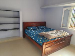 a bedroom with a wooden bed with blue sheets at SM GARDENS Luxury Homestay in Oothu