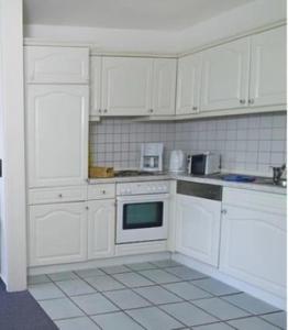 a white kitchen with white cabinets and appliances at Ruth Sonnenhut in Wulfen auf Fehmarn