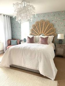 Un dormitorio con una gran cama blanca y una lámpara de araña. en Hibiscus House, en Shilton