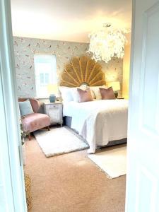 1 dormitorio con 1 cama, 1 silla y 1 lámpara de araña en Hibiscus House, en Shilton