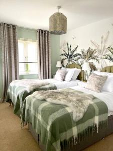 a bedroom with two beds with green and white blankets at Hibiscus House in Shilton