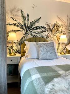 a bedroom with a bed with plants on the wall at Hibiscus House in Shilton