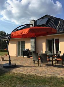 a patio with a table and a red umbrella at Ferienhaus Plauer See in Alt Schwerin
