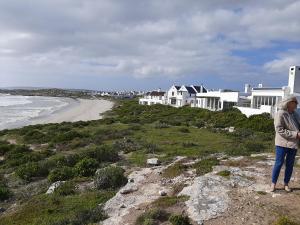 Eine Frau, die auf einem Hügel am Strand steht. in der Unterkunft Milk Thistle Loft & Studio apartments in Paternoster