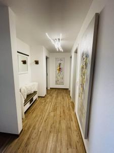 einen Flur mit weißen Wänden, Holzböden und Gemälden in der Unterkunft Neue Ferienwohnung mit Whirlpool und Sauna in der Residenz Grafenmatt inklusive HochschwarzwaldCard in Feldberg