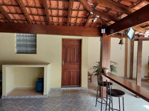 a room with a wooden door and two stools at Recanto Do Sossego Suítes Hospedagem Domiciliar na Praia in Boicucanga