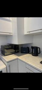 a kitchen with white cabinets and a microwave at Cap d ail 2 pièces proches Monaco et plage in Saint-Antoine