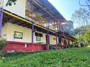 a building with a large balcony and a green field at alojamiento rural finca ayapel in Verdún