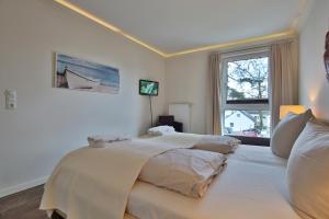 1 dormitorio con 1 cama blanca grande y ventana en Domizil am Meer Domizil am Meer Appartement 16 en Timmendorfer Strand