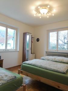 two beds in a room with two windows at Dimai House 1970s in Hohenems