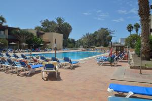 a swimming pool with lounge chairs and a resort at CALO BEACH in Costa Del Silencio