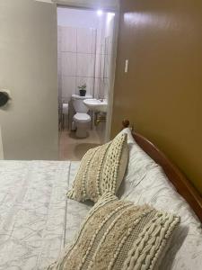a bedroom with a bed and a bathroom with a toilet at Cozy Quarters Tobago in Scarborough