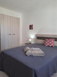 una camera da letto con un letto blu con due asciugamani di Apartamento Orla-Mar a Vila Nova de Cacela