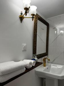 a bathroom with a sink and a mirror and towels at Maison Riquet in Castelnaudary