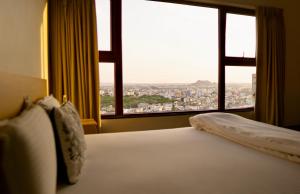 a bed in a hotel room with a large window at Bridge Service Apartment in Hyderabad