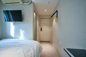 - une chambre avec un lit et une télévision murale dans l'établissement Life in Euljiro, à Séoul