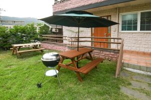 a grill and a picnic table with an umbrella at Yeonhwachon Pension in Jeju