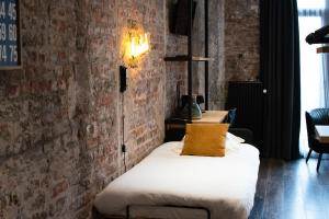 a bed in a room with a brick wall at Upstairs Hotel in Ostend