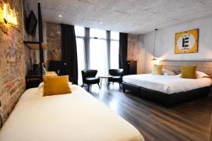 a hotel room with two beds and a table and chairs at Upstairs Hotel in Ostend