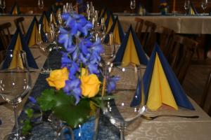 a table with wine glasses and blue and yellow flowers at Gasthof Dorfwirt in Ardning