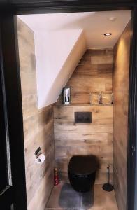 a bathroom with a black toilet and wooden walls at Het Blij Hoen in Oudenbosch
