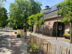 a brick house with a wooden fence next to a street at Het Blij Hoen in Oudenbosch