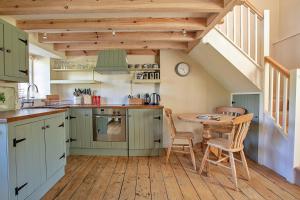 a kitchen with green cabinets and a table with chairs at Finest Retreats - The Laundry Cottage in Newquay