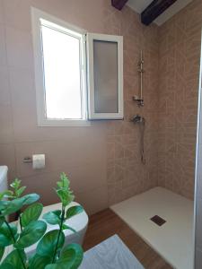 uma casa de banho com um chuveiro, um WC e uma janela. em El Fresno Cazorla em Coto Rios