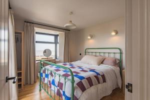 a bedroom with a bed with a colorful blanket and a window at Victory Cottage - Stunning home with sea views in Kingsdown