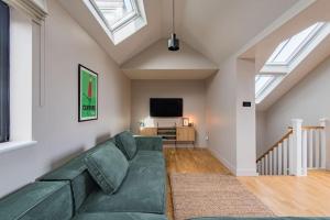 a living room with a green couch and a tv at Victory Cottage - Stunning home with sea views in Kingsdown