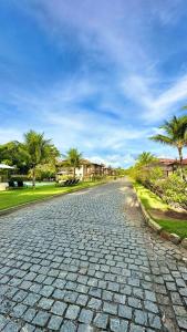 a cobblestone street with palm trees and houses at Apartamento na Vila La Torre in Porto Seguro