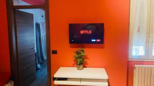 ein Wohnzimmer mit einer orangefarbenen Wand und einem TV in der Unterkunft Gemma Apartments Milano Rho Fiera Apt2 in Lainate