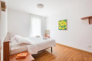 a white bedroom with a bed and a table at Appartamenti Gabry in Riva del Garda