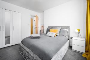 a bedroom with a large gray bed with orange pillows at BROADWAY SUITE - Newly refurbished stylish apartment with FREE PRIVATE PARKING - Great location in Birmingham