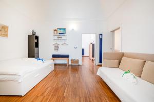 ein Wohnzimmer mit 2 weißen Betten und Holzboden in der Unterkunft Marina Terrace Apartment in Mola di Bari