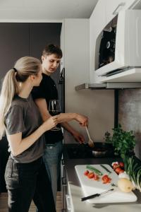 un uomo e una donna in una cucina con un bicchiere di vino di Aurora Fjord Cabins a Lyngseidet