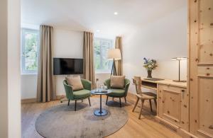 a hotel room with a table and chairs and a desk at Parkhotel Margna Superior in Sils Maria