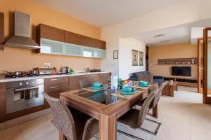 eine Küche mit einem Tisch und Stühlen im Zimmer in der Unterkunft Harbour Views Gozitan Villa Shared Pool - Happy Rentals in Mġarr