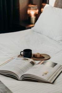 ein Buch auf einem Bett mit einer Tasse und einem Teller Essen in der Unterkunft Aurora Fjord Cabins in Lyngseidet