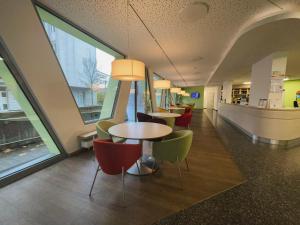 uma cafetaria com mesas, cadeiras e janelas em Jugendherberge Braunschweig em Braunschweig