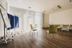 a room with chairs and a table and a board at Jugendherberge Braunschweig in Braunschweig
