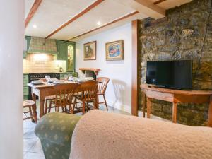 a living room with a table and a kitchen with a tv at The Lymings in Lyme Regis