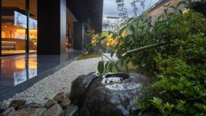 un jardin avec un chat assis sur un rocher dans l'établissement Onn Yuda Onsen, à Yamaguchi
